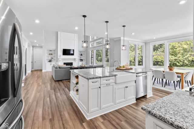 78 Chatham Brook Dr, Westfield, IN 46074 - kitchen with appliances with stainless steel finishes, a sink, wood finished floors, white cabinetry, and an island with sink