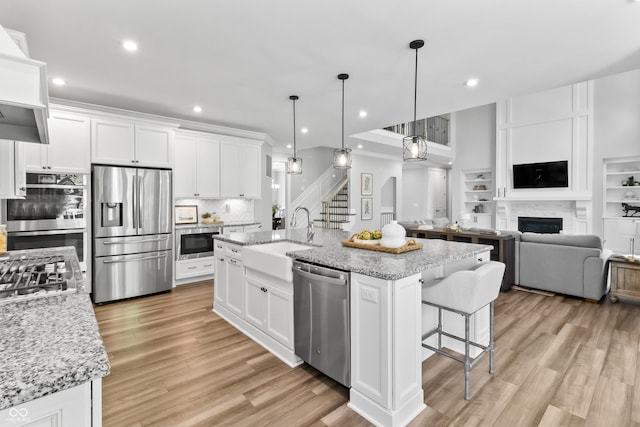 78 Chatham Brook Dr, Westfield, IN 46074 - kitchen featuring appliances with stainless steel finishes, a sink, a fireplace, backsplash, and white cabinets