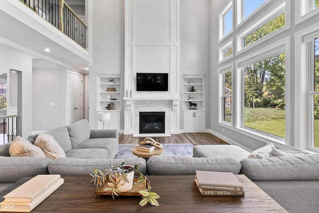 78 Chatham Brook Dr, Westfield, IN 46074 - living room with a towering ceiling, wood finished floors, a glass covered fireplace, built in features, and baseboards