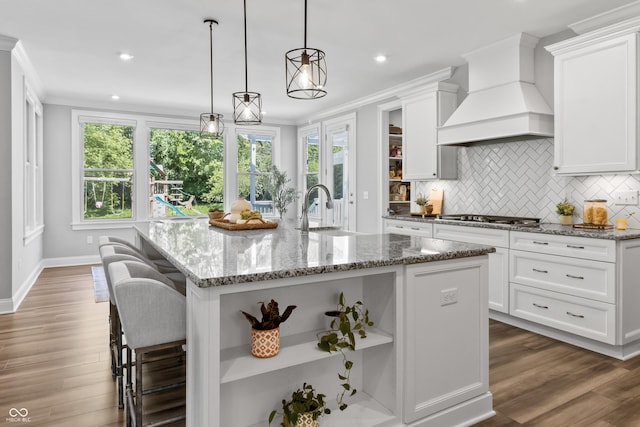 78 Chatham Brook Dr, Westfield, IN 46074 - kitchen featuring a sink, open shelves, custom exhaust hood, stainless steel gas cooktop, and a center island with sink