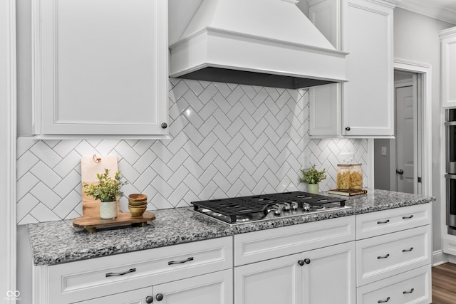 78 Chatham Brook Dr, Westfield, IN 46074 - kitchen with custom exhaust hood, stainless steel gas stovetop, backsplash, white cabinetry, and light stone countertops