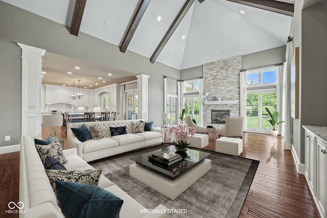 living room with a stone fireplace, dark hardwood / wood-style floors, high vaulted ceiling, decorative columns, and beam ceiling