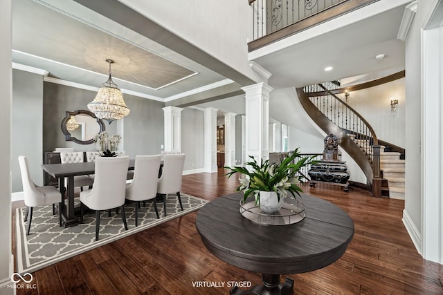 dining space featuring dark wood-type flooring, ornamental molding, decorative columns, and a notable chandelier