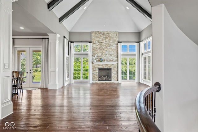 living room featuring a stone fireplace, dark hardwood / wood-style floors, high vaulted ceiling, beam ceiling, and french doors