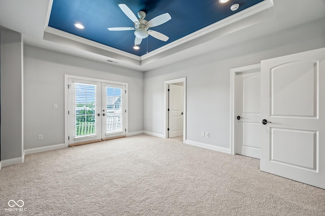 interior space featuring crown molding, a tray ceiling, light colored carpet, and french doors