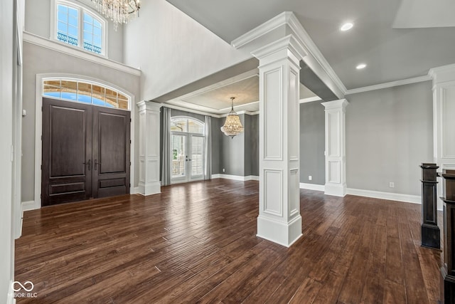 entryway with decorative columns, a notable chandelier, crown molding, dark wood-type flooring, and french doors