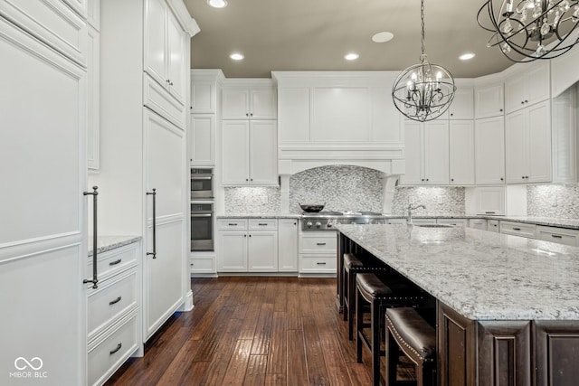 kitchen featuring pendant lighting, white cabinetry, a breakfast bar area, dark hardwood / wood-style flooring, and a kitchen island with sink