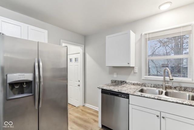 kitchen with light hardwood / wood-style floors, white cabinetry, sink, stainless steel appliances, and light stone counters