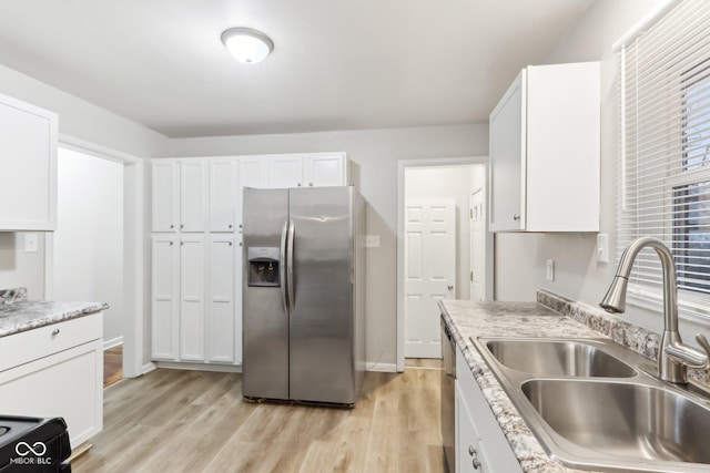 kitchen featuring light stone countertops, appliances with stainless steel finishes, sink, white cabinets, and light hardwood / wood-style flooring