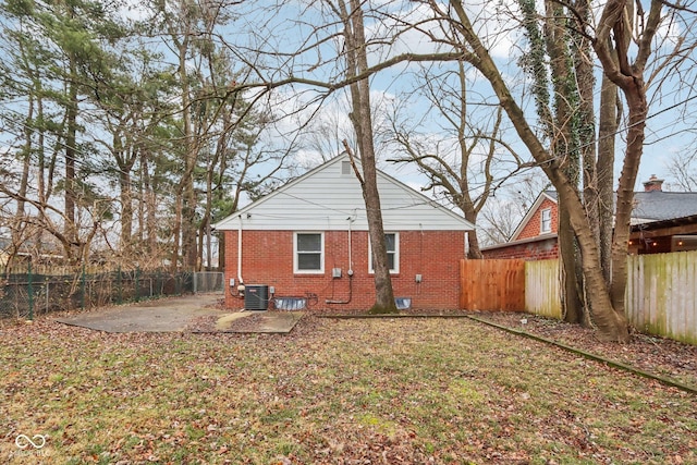 back of house with central air condition unit, a patio area, and a lawn