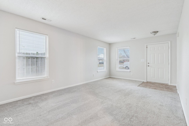 empty room with light colored carpet and a textured ceiling