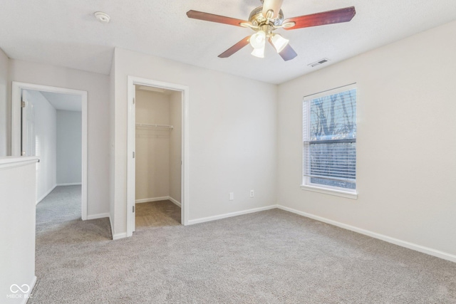 unfurnished bedroom with ceiling fan, light colored carpet, a spacious closet, and a closet