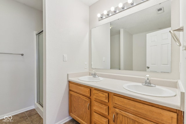 bathroom with a shower with shower door, tile patterned floors, and vanity