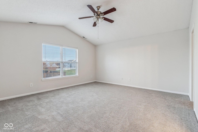 carpeted spare room with a textured ceiling, vaulted ceiling, and ceiling fan