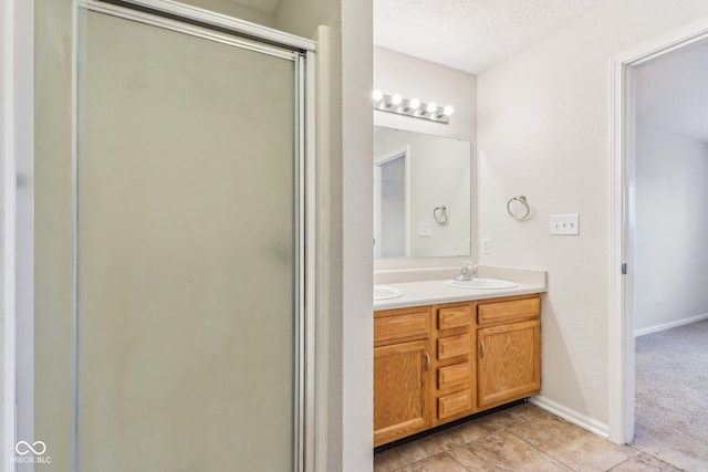 bathroom with a textured ceiling, walk in shower, tile patterned floors, and vanity