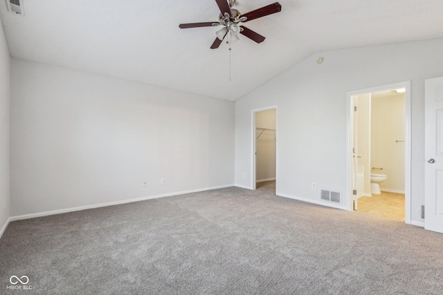 unfurnished bedroom featuring a spacious closet, ensuite bath, carpet flooring, vaulted ceiling, and ceiling fan