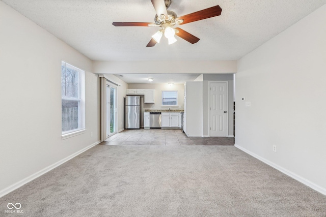 unfurnished living room with a textured ceiling, light colored carpet, and ceiling fan