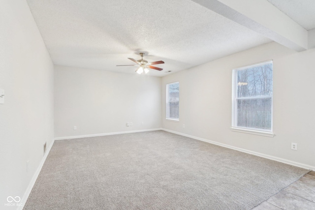 empty room featuring ceiling fan, a textured ceiling, and beam ceiling