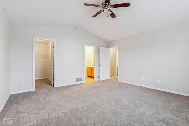 unfurnished bedroom with ceiling fan, light colored carpet, a spacious closet, connected bathroom, and a closet