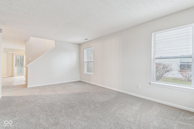 carpeted spare room with a textured ceiling