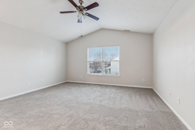 carpeted empty room with vaulted ceiling, ceiling fan, and a textured ceiling