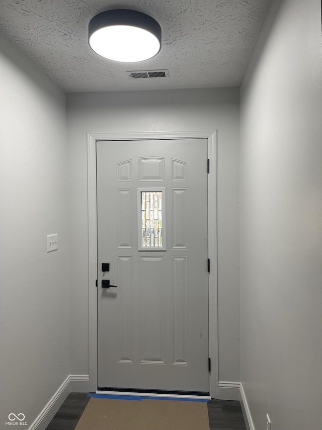 doorway to outside with dark hardwood / wood-style flooring and a textured ceiling