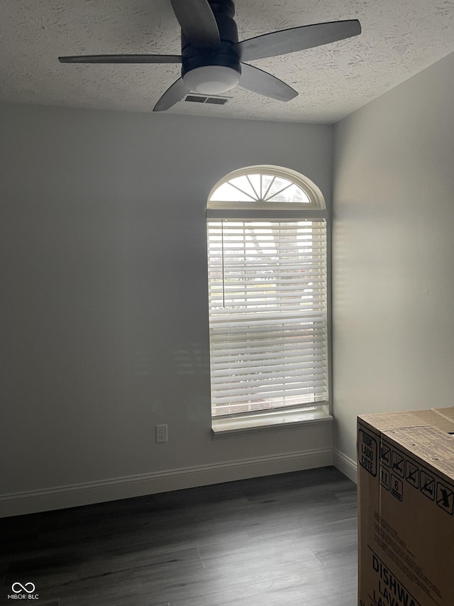 spare room featuring ceiling fan, dark hardwood / wood-style flooring, and a textured ceiling