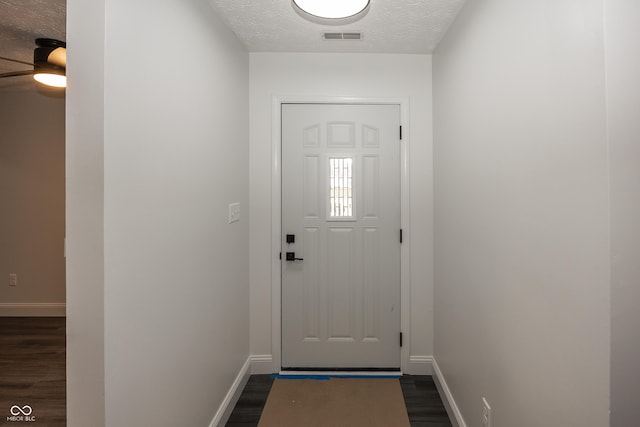 doorway to outside with ceiling fan, dark hardwood / wood-style flooring, and a textured ceiling