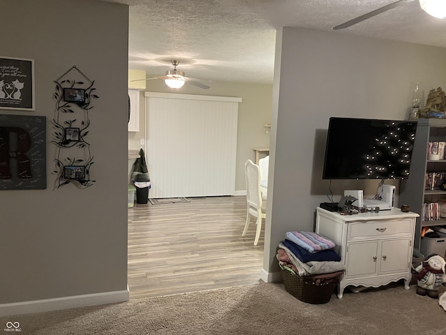 living room featuring ceiling fan, light colored carpet, and a textured ceiling