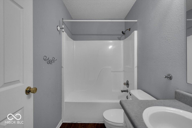 full bathroom featuring vanity, a textured ceiling, bathing tub / shower combination, wood-type flooring, and toilet