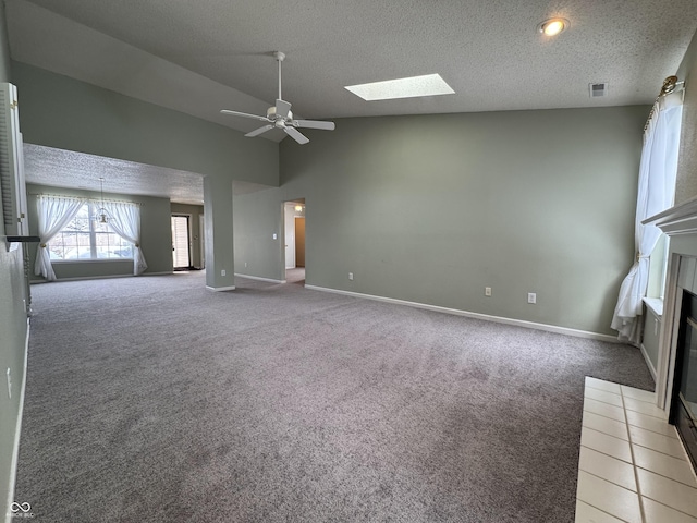 unfurnished living room with a skylight, ceiling fan, carpet, and a textured ceiling