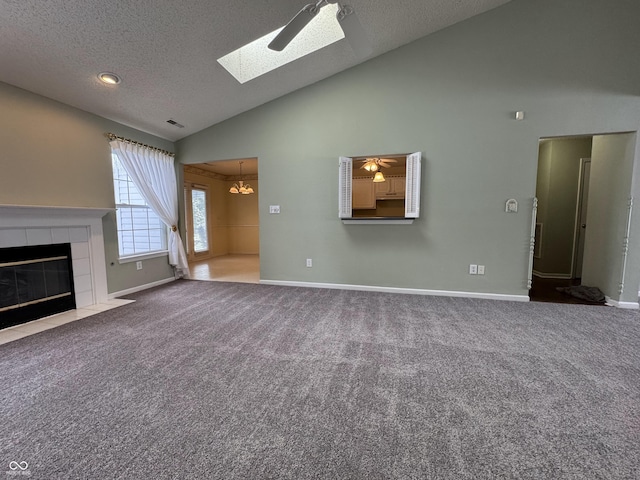 unfurnished living room with a textured ceiling, ceiling fan with notable chandelier, a tile fireplace, high vaulted ceiling, and carpet floors