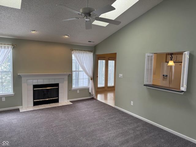 unfurnished living room with carpet, a textured ceiling, vaulted ceiling, ceiling fan, and a tile fireplace