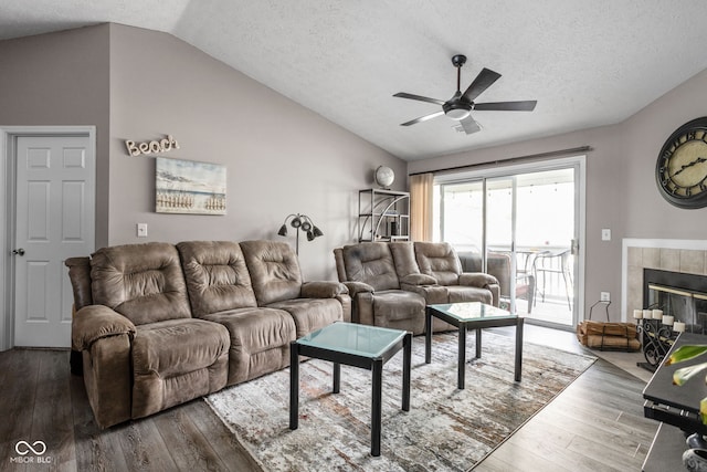 living room with lofted ceiling, ceiling fan, a fireplace, a textured ceiling, and wood-type flooring