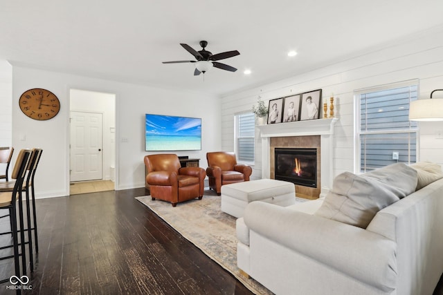 living room with a tile fireplace, ceiling fan, and hardwood / wood-style flooring