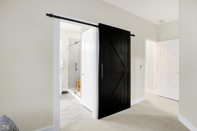 hall with a barn door and light colored carpet