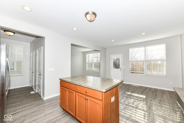 kitchen featuring stainless steel refrigerator, a center island, a healthy amount of sunlight, and light wood-type flooring