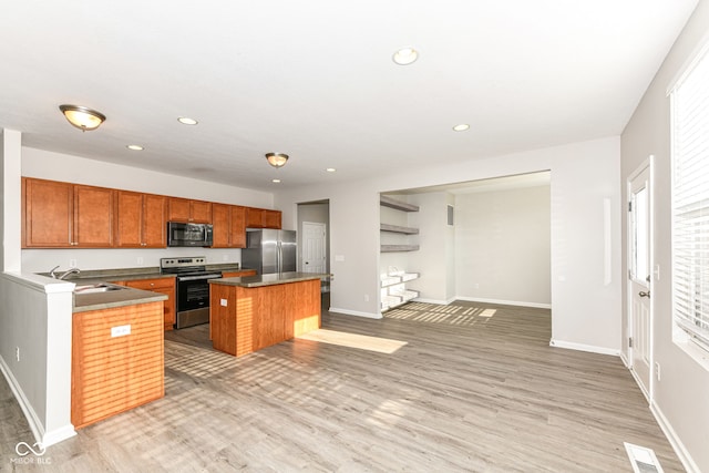 kitchen featuring sink, stainless steel appliances, light hardwood / wood-style flooring, a kitchen bar, and a kitchen island