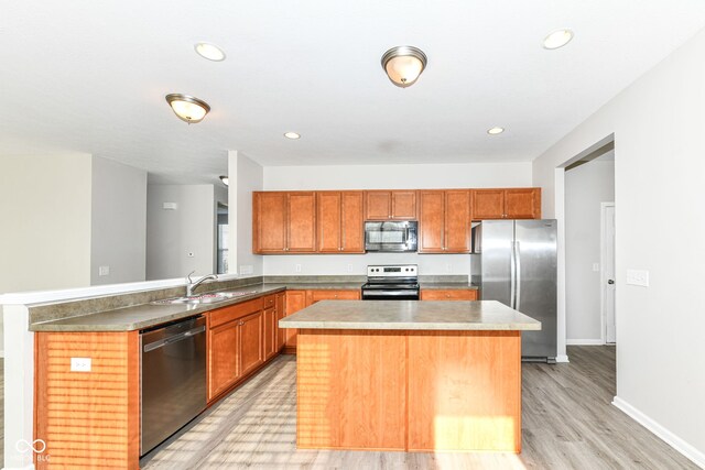 kitchen with a center island, sink, appliances with stainless steel finishes, light hardwood / wood-style floors, and kitchen peninsula