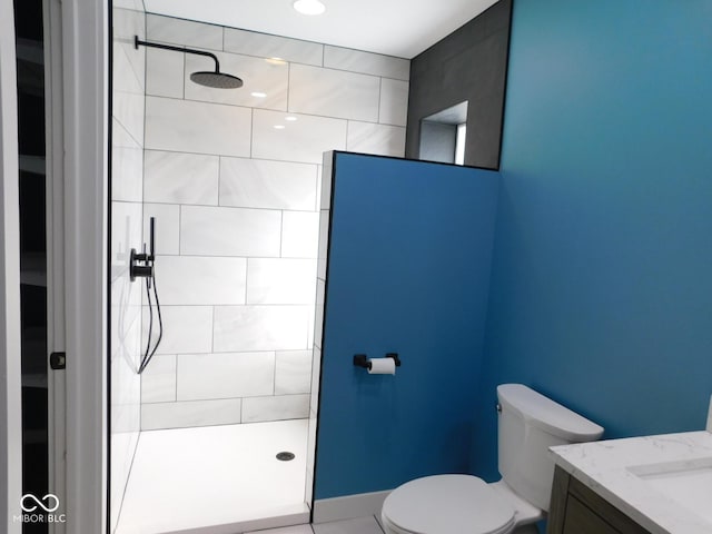 bathroom with vanity, a tile shower, and toilet