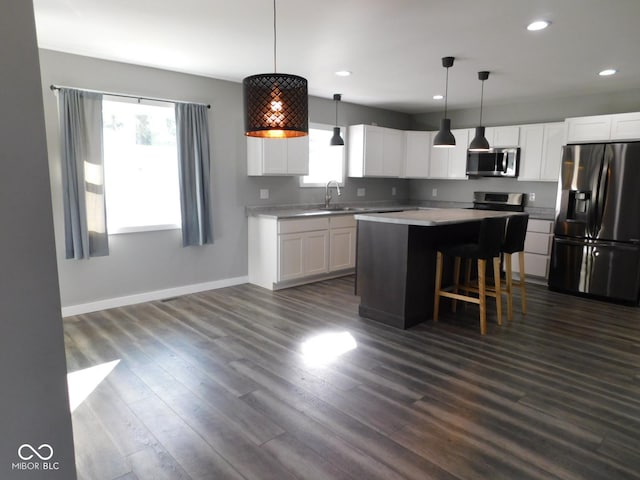 kitchen with white cabinetry, stainless steel appliances, a center island, and hanging light fixtures