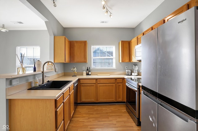 kitchen featuring plenty of natural light, sink, appliances with stainless steel finishes, and light hardwood / wood-style flooring