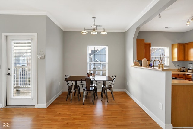 dining room with light hardwood / wood-style floors and crown molding