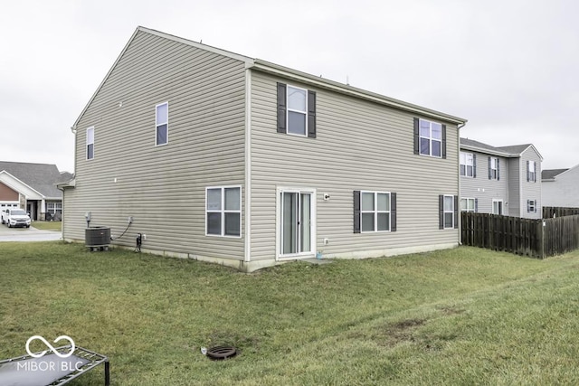 rear view of house featuring cooling unit and a lawn