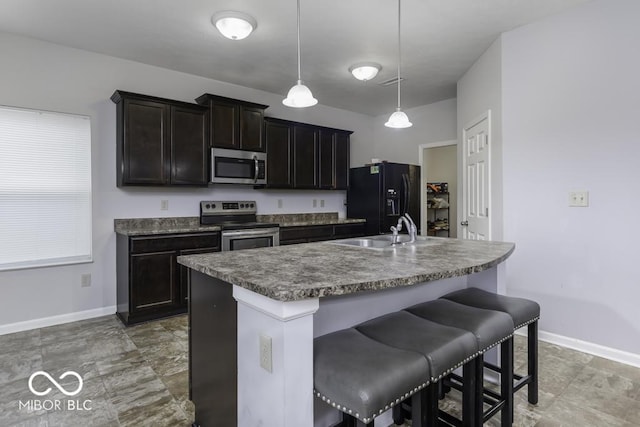 kitchen featuring sink, stainless steel appliances, a kitchen breakfast bar, pendant lighting, and a kitchen island with sink