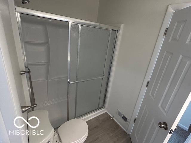 bathroom with hardwood / wood-style floors, toilet, and walk in shower