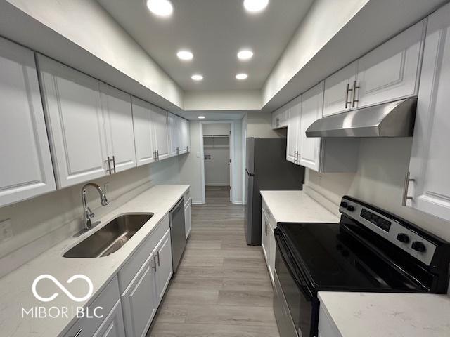 kitchen with appliances with stainless steel finishes, light wood-type flooring, white cabinetry, and sink