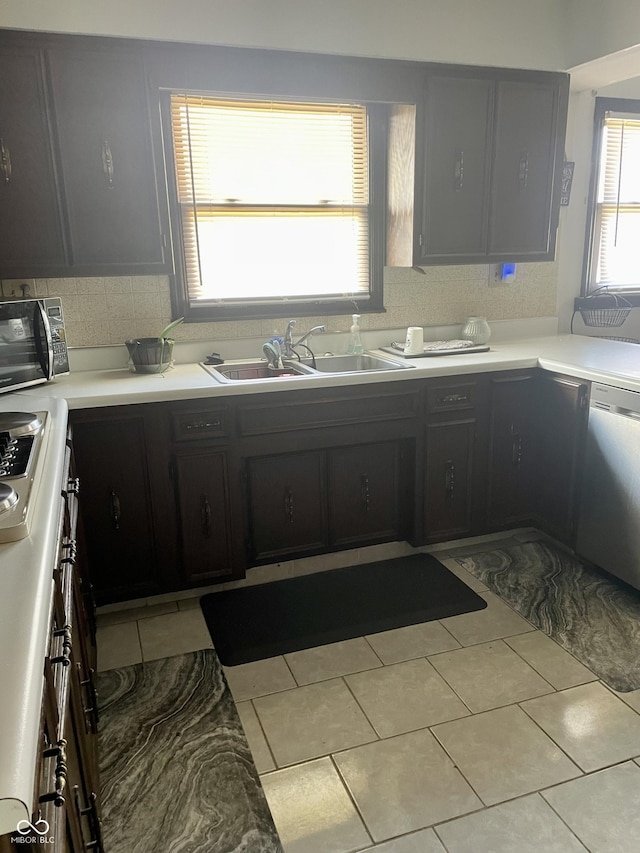 kitchen featuring dishwasher, light tile patterned floors, stovetop, and sink