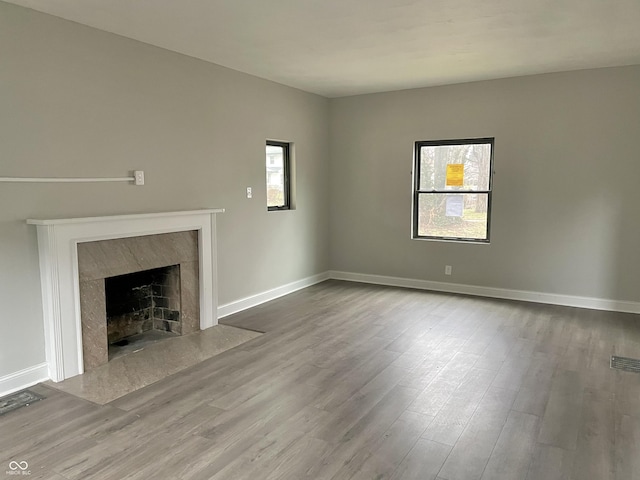 unfurnished living room featuring plenty of natural light, a premium fireplace, and hardwood / wood-style floors