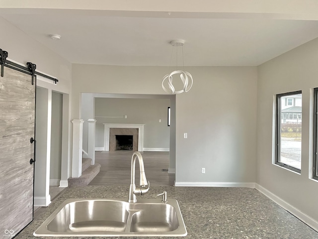 kitchen with hanging light fixtures, a barn door, sink, and a premium fireplace